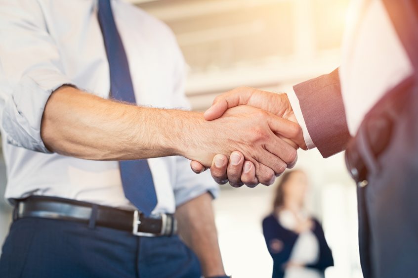 Businessmen shaking hands during a meeting. Closeup of business handshake between two colleagues in a modern office. Successful businessmen handshaking closing a deal. Agreement and business concept.